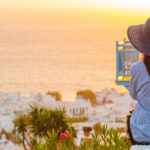 Young Woman is Looking at the Sunset Over A Sea In Famous Mykonos Greece